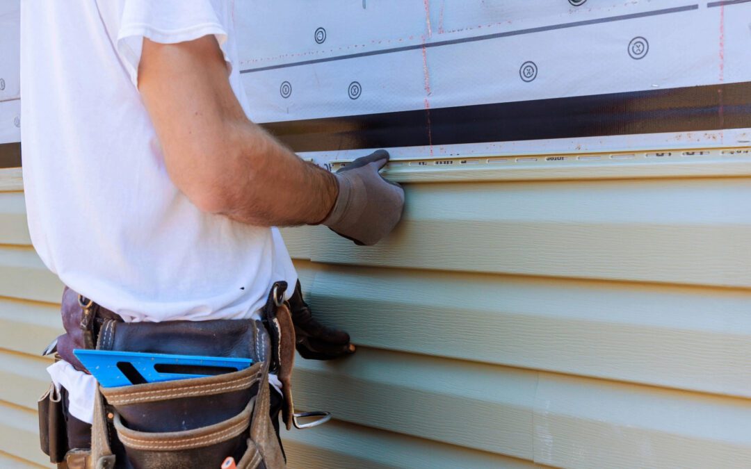 Professional installer working with beige vinyl siding on a residential home—JC Siding & Construction, a trusted choice for siding companies near me.